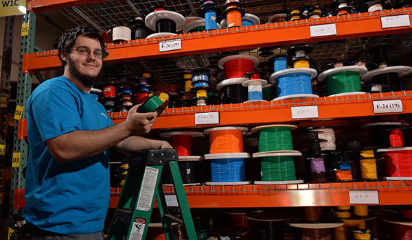 Employee picking wire spool from storage
